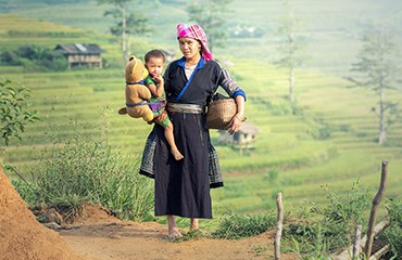 Female farm worker carries child while working in field