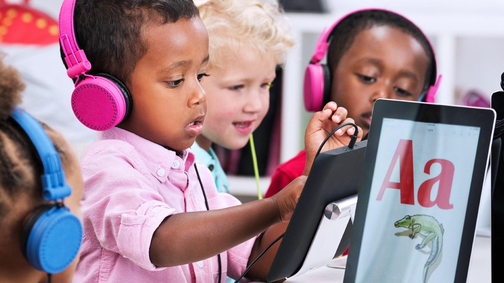 Children with headphones using tablets