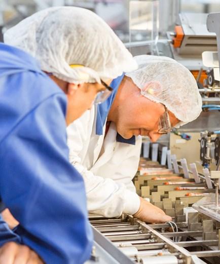 Two Male Factory Workers looking into their equipment.