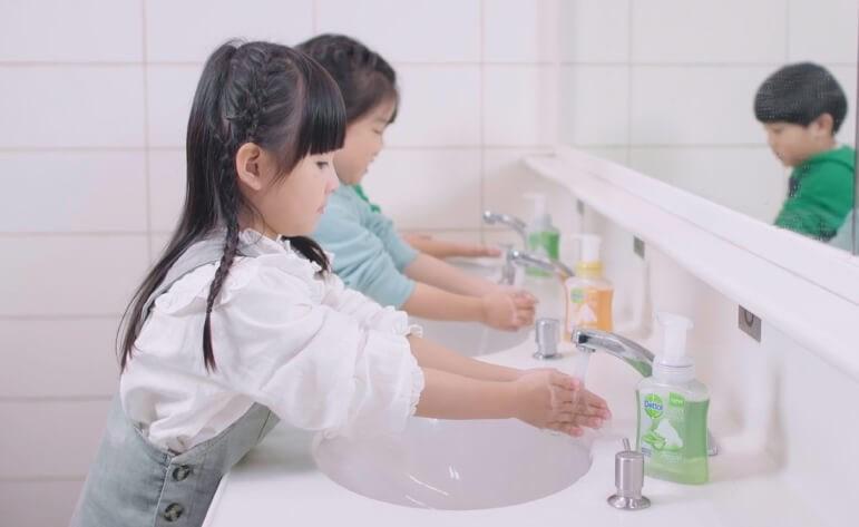 Children wash their hands with Dettol soap in a communal bathroom.