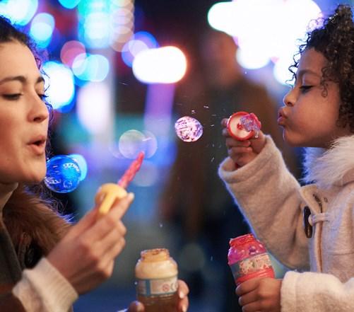 Adult and child blowing soap bubbles at night