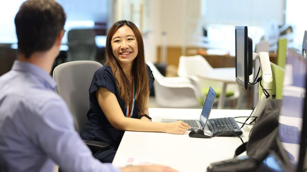 Young woman sitting at a desk and smiling at her colleague