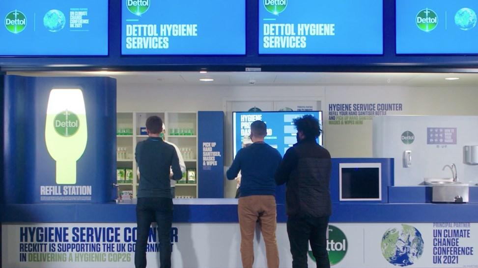 Three people standing in front of a COP26 Dettol counter.