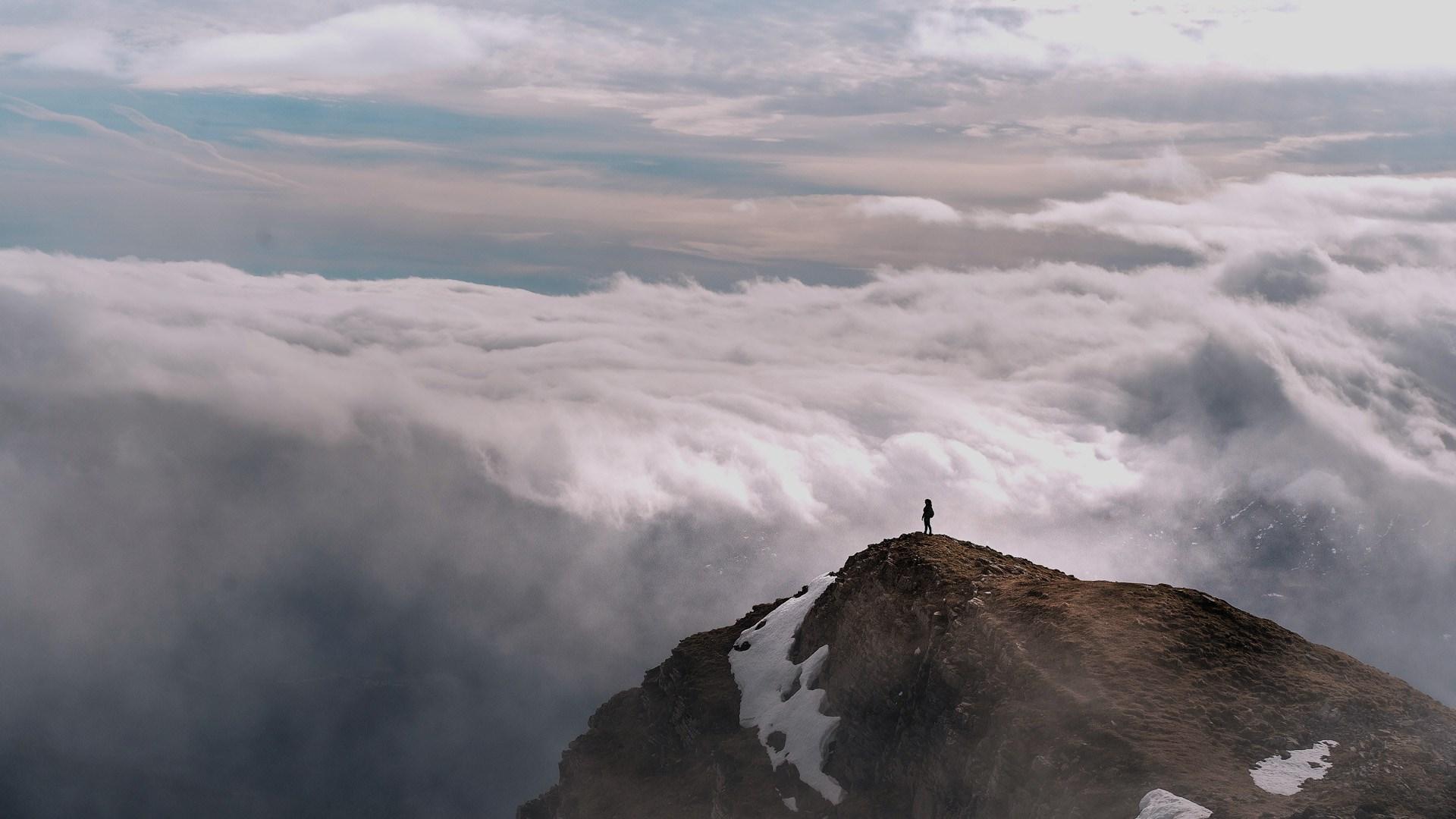 Beautiful view from the top of a mountain and a woman looking at the awesome cloud scape from above.