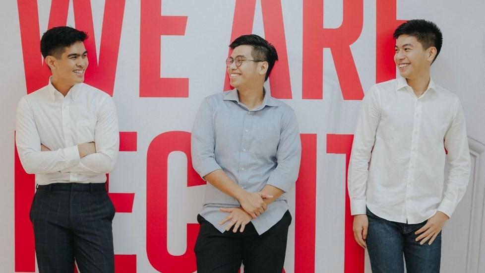Three young men smiling against a wall which reads 'We are Reckitt'